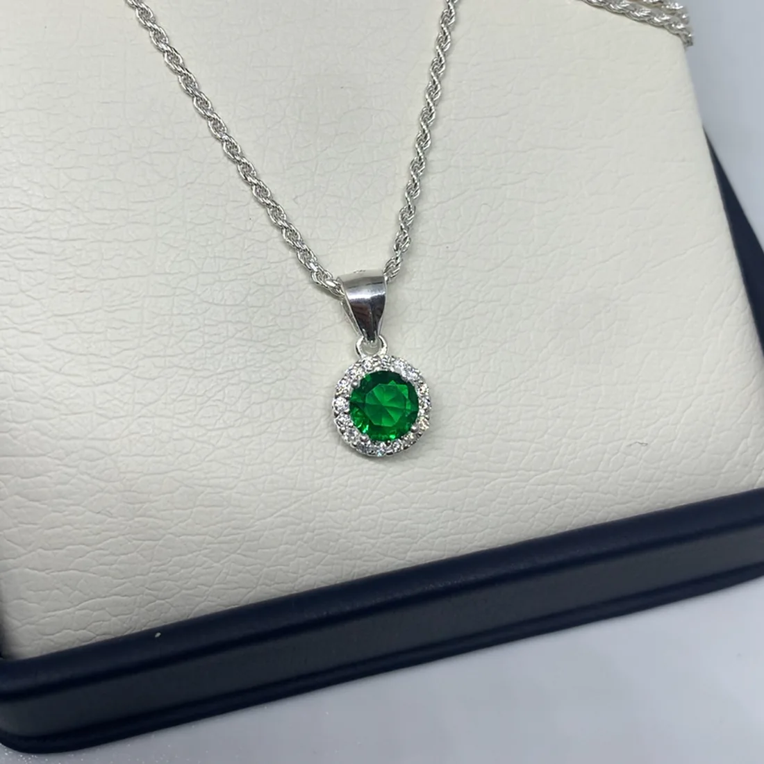 Cadena en plata con dije circular de esmeralda y halo de circones